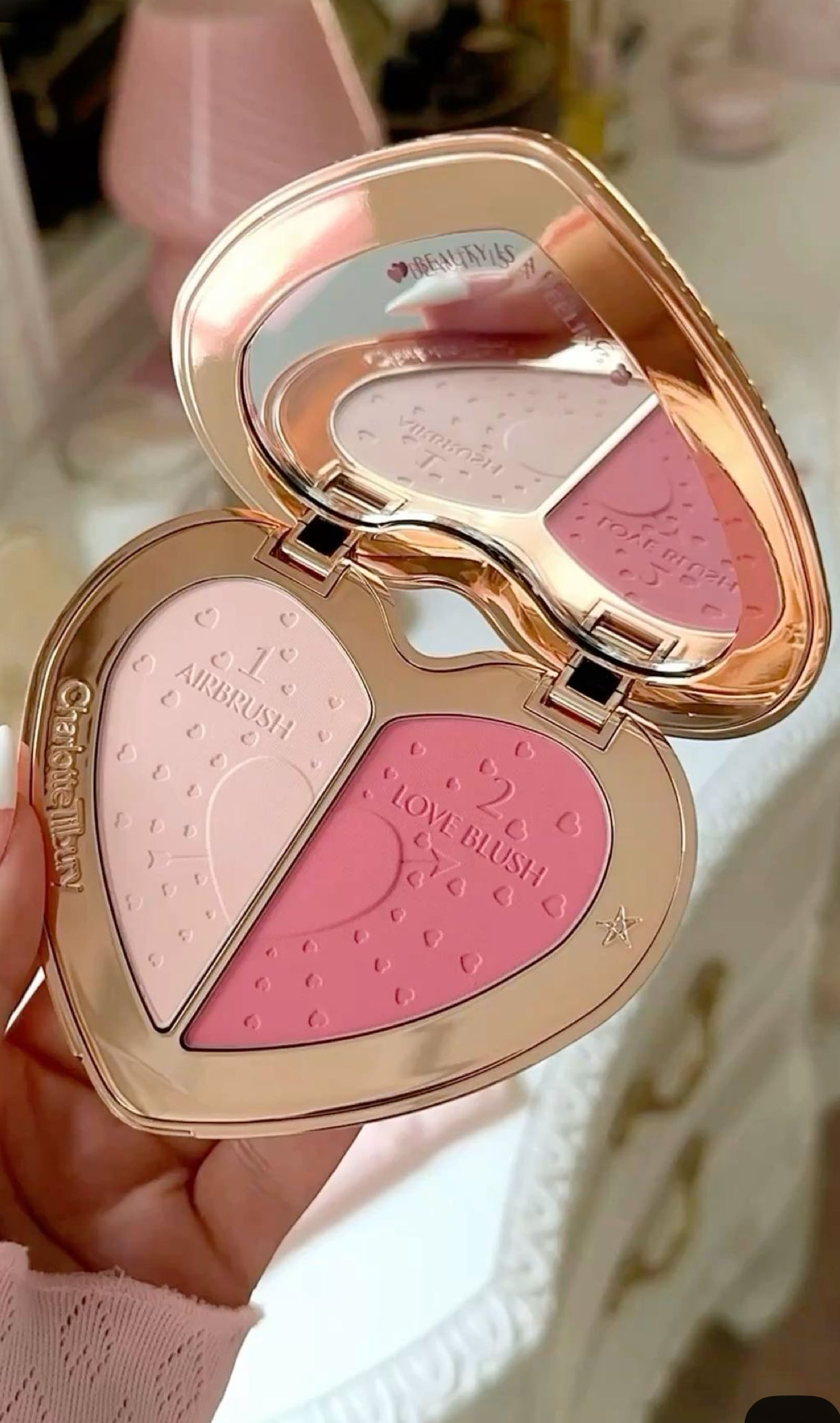 Makeup compact with blushes held by a hand against a blurred background